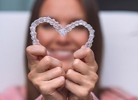 Woman holding Invisalign trays in the shape of a heart