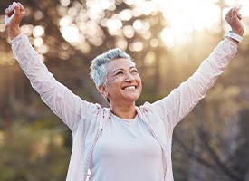Smiling woman outside stretching arms out victoriously