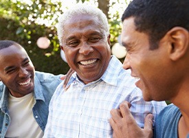 Three men outside smiling and talking together