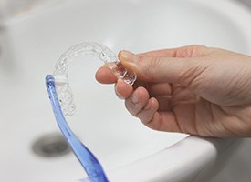 Hands brushing Invisalign tray