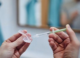 A man applying bleaching gel to a teeth whitening tray