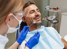 Man in dental chair smiling about to undergo exam