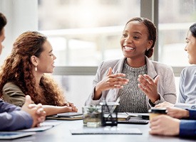 Group of professionals sitting around a table discussing something with folders and tablets