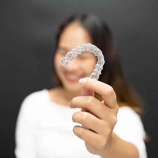 Woman holding a single Candid clear aligner in Chevy Chase, MD