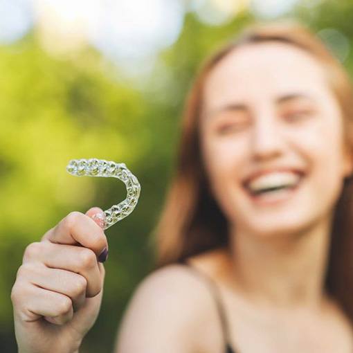 Woman laughing and holding a Candid clear aligner in Chevy Chase, MD