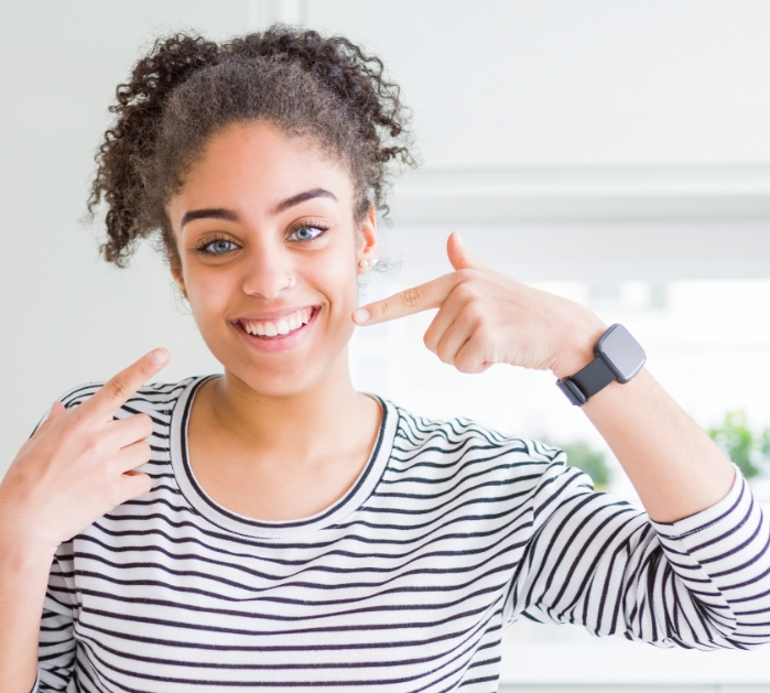 Woman pointing to smile after preventive dentistry