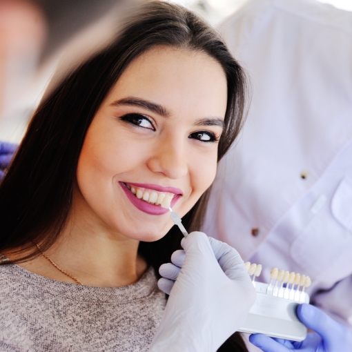 Woman's smile compared with dental bonding color chart