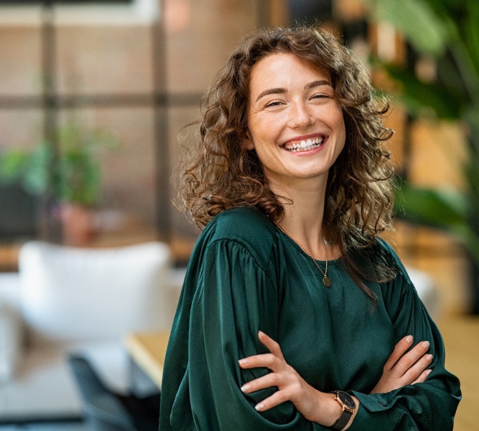 young woman smiling while crossing arms
