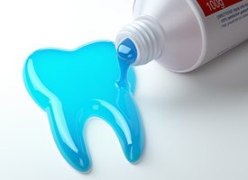 Blue liquid coming out of a bottle and forming the shape of a tooth