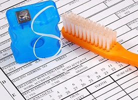 Insurance form with floss and a toothbrush on top of it
