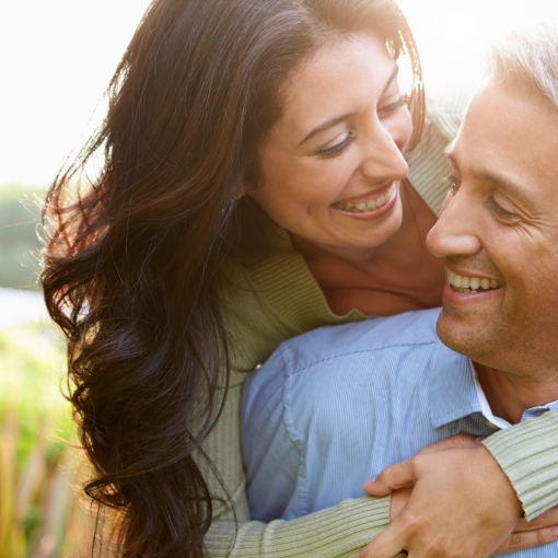 Man and woman smiling together after the four step dental implant process