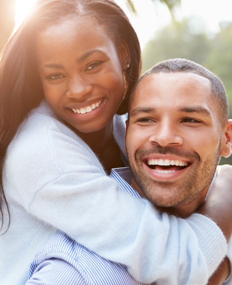 Man and woman smiling and holding each other outdoors
