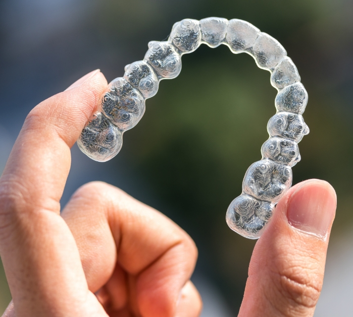 Hand holding a clear orthodontics tray for smile alignment