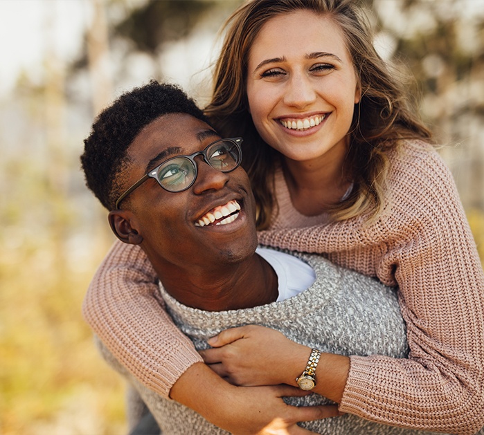 Man and woman with healthy smiles after replacing missing teeth