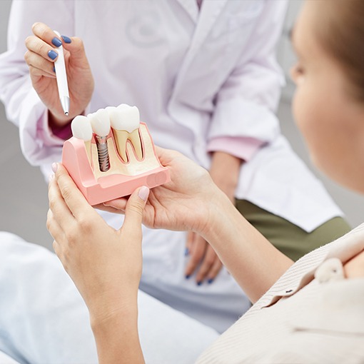 Dentist and patient looking at dental implant model