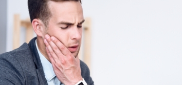 Man holding jaw in pain before TMJ therapy