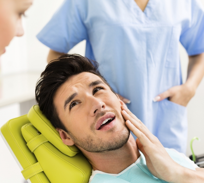 Man holding jaw in pain before T M J therapy