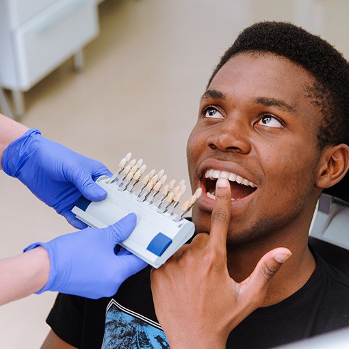 a man pointing to his tooth while sitting in a dental chair