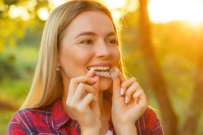 A woman placing clear aligners over her teeth