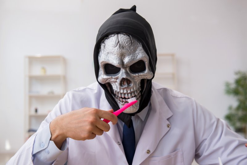 A dentist wearing a Halloween mask and holding a toothbrush