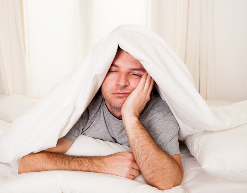 Man under blanket looking tired