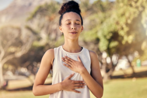 Woman resting her hands on her chest as she takes a deep breath
